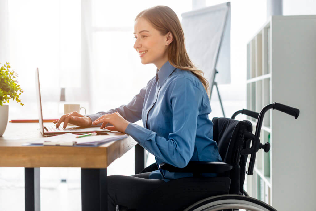 Mujer en silla de  ruedas trabajando con un ordenador.